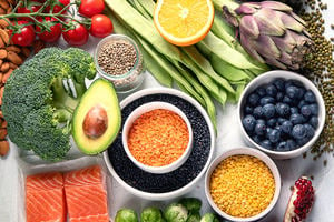 Selection of healthy food. Clean eating concept. Cooking ingredients with fish, superfood, vegetables, artichokes, brussel sprouts, fruits, legumes and blueberries.