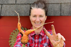 A woman holds a misshapen carrot
