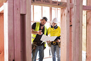 Male and female construction workers discuss a building plan