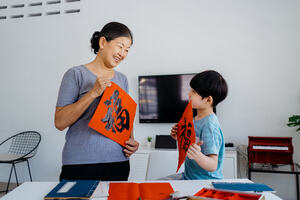 Senior asian woman writing chinese calligraphy with her grandson
