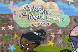 Street art of a young girl riding on a bike, with stars upon the sky and a big cloud with the message 'Make the World Green Again!', to represent sustainability and climate action.