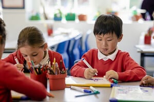 Two school pupils focusing on drawing with whiteboards.
