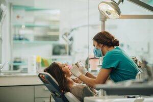 a dentist using instruments to give a woman dental treatment 