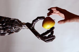 Human hand taking an apple from a robot hand