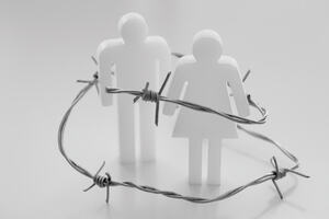 doll of a man and a women surrounded by barbed wire