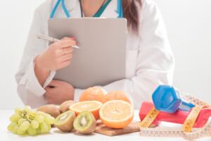 Clinician holding clipboard in front of healthy foods and exercise equpment