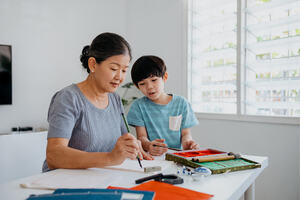 Senior asian woman teaching her grandson Chinese calligraphy 