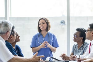 Female healthcare expert educating a table of other healthcare professionals 