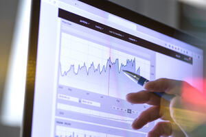 Closeup of a stock broker's hand analyzing the performance of a company stock on the internet on a price chart.