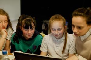 A female teacher and three girls looking at a computer screen