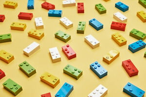 A selection of different LEGO Braille Bricks on a yellow table