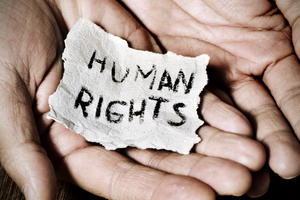 The inscription "human rights" written on a little piece of paper held between two hands 