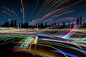 A darkened city skyline with many coloured lines crossing in all directions 