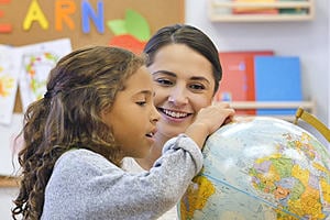 a teacher and a student looking at a globe